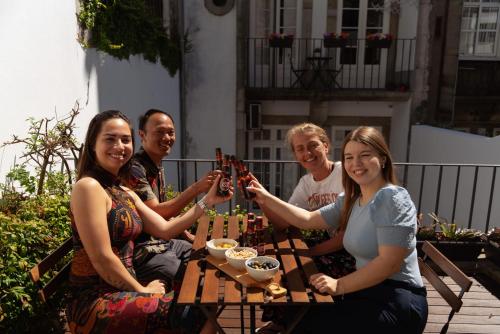 a group of people sitting around a table holding up wine bottles at Porto Lounge Hostel & Guesthouse by Host Wise in Porto