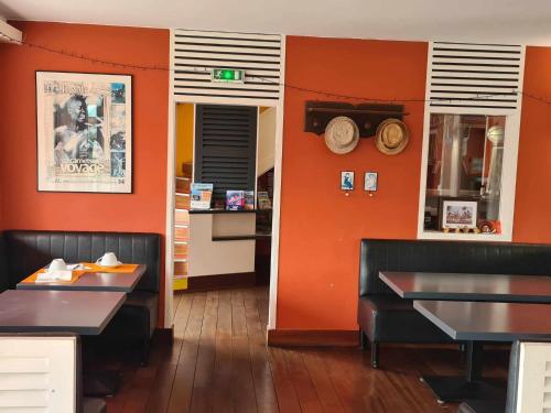 a restaurant with orange walls and black tables and chairs at Hotel Cap D'Ambre in La Barre-de-Monts