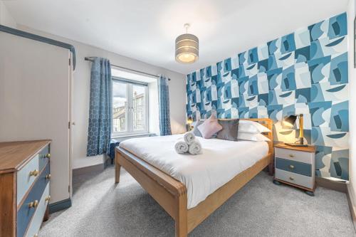 a bedroom with a bed with a blue and white headboard at Blue Sky Cottage in Keswick