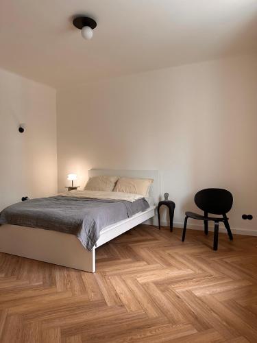 a white bedroom with a bed and a chair at Apartament przy Łazienkach Królewskich in Warsaw