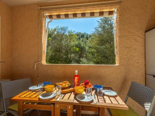 une table en bois avec des assiettes de nourriture et une fenêtre dans l'établissement Studio Hauts de la Madrague-13 by Interhome, à Saint-Cyr-sur-Mer