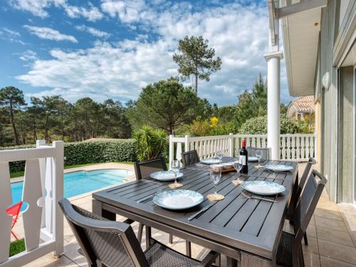 - une terrasse en bois avec une table et des chaises à côté de la piscine dans l'établissement Holiday Home Atlantic Green by Interhome, à Lacanau-Océan