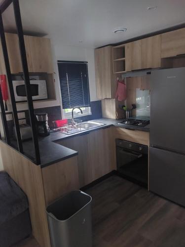 a kitchen with wooden cabinets and a black refrigerator at mobil home jordy a gastes 714 in Gastes