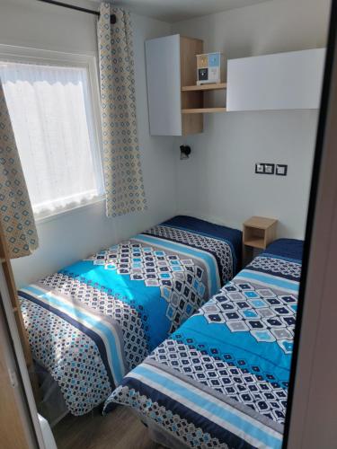 two twin beds in a room with a window at mobil home jordy a gastes 714 in Gastes