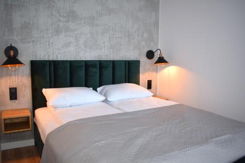 a bedroom with a large bed with a green headboard at Apartos Seaside Garden Luxury Apartments in Świnoujście