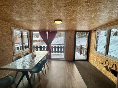 une salle à manger avec une table, des chaises et des fenêtres dans l'établissement chalet proche des pistes Ô chalet Dana, à Vars