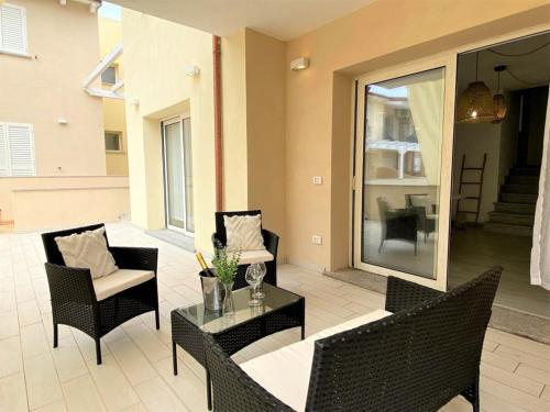 特里尼塔迪亞古圖的住宿－Apartment Perla dell'Isola by Interhome，庭院配有椅子、桌子和玻璃桌