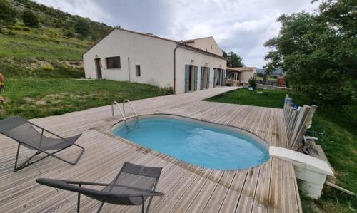 a swimming pool on a deck with two chairs and a house at Studio au cœur du Verdon in La Palud sur Verdon