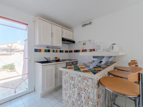 une cuisine avec des armoires blanches et un comptoir avec des tabourets dans l'établissement Holiday Home Le Clos du Par by Interhome, à Saint-Cyprien