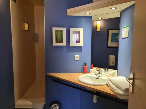 een blauwe badkamer met een wastafel en een spiegel bij Hotel Cap D'Ambre in La Barre-de-Monts
