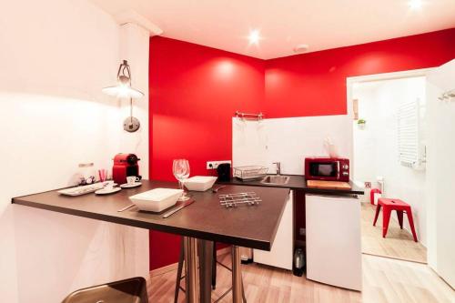 a kitchen with red walls and a black counter at The studio at Saint-Jean cathedral, old town AIL in Lyon