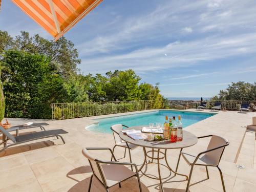 un patio avec une table et des chaises à côté d'une piscine dans l'établissement Holiday Home Le Chardin by Interhome, à Saint-Aygulf