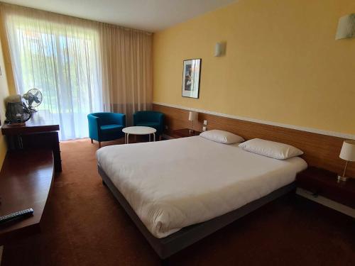 a hotel room with a large bed and chairs at Hotel Cap D'Ambre in La Barre-de-Monts