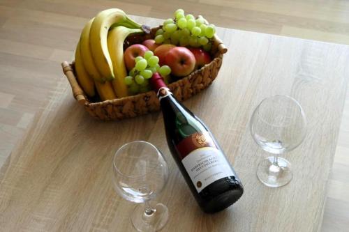 a bottle of wine next to a basket of fruit at Ferienwohnung Geyersberg in Freyung