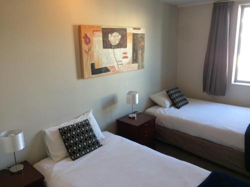 a hotel room with two beds and a painting on the wall at City Central Motel Apartments in Christchurch