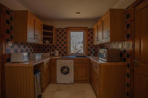 a kitchen with a washer and dryer in it at Castlebay View in Castlebay