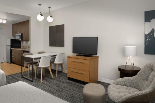 a living room with a tv and a table and chairs at TownePlace Suites by Marriott Cheyenne Southwest/Downtown Area in Cheyenne