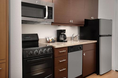 a small kitchen with a black stove and refrigerator at TownePlace Suites by Marriott Cheyenne Southwest/Downtown Area in Cheyenne