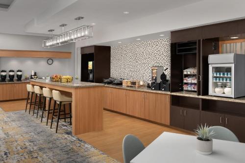 a kitchen with wooden cabinets and a bar with stools at TownePlace Suites by Marriott Cheyenne Southwest/Downtown Area in Cheyenne