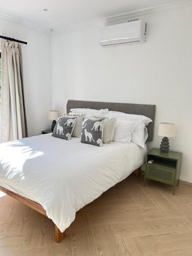 a bedroom with a large bed with white sheets and pillows at Chasselas Self Catering in Cape Town