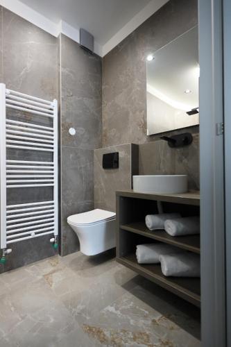 a bathroom with a toilet and a sink and a mirror at Zen Private Suites in Ioannina