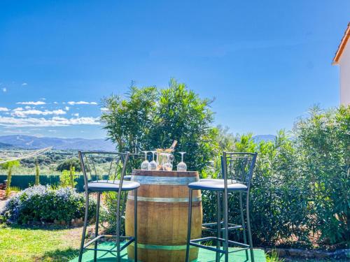 deux tabourets de bar assis devant un tonneau dans l'établissement Holiday Home Les Lauriers Blancs by Interhome, à Vidauban