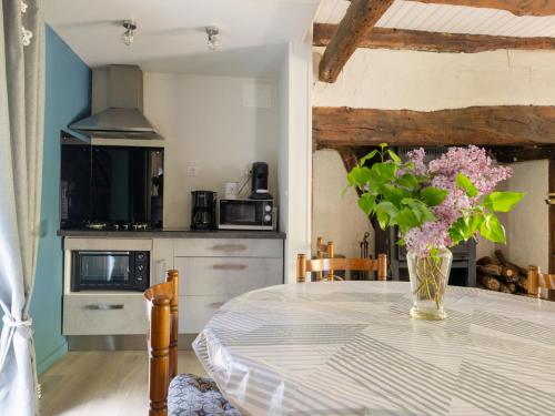 a kitchen with a table with a vase of flowers on it at Holiday Home Roucan by Interhome in Teyssieu