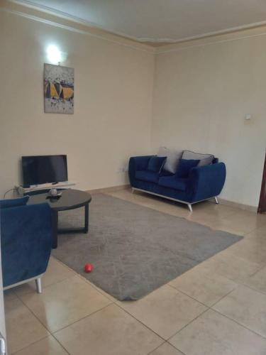a living room with a blue couch and a table at Serene 1 Bedroom Cozy Apartment in a fancy mall in Najjera in Kampala