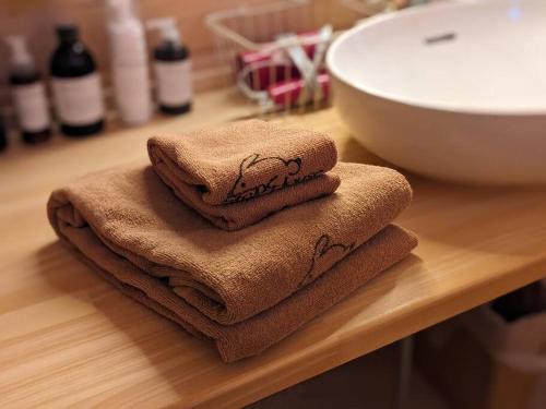 a pile of towels sitting on a counter next to a sink at Log cabin rentals & Finland sauna Step House in Yamanakako