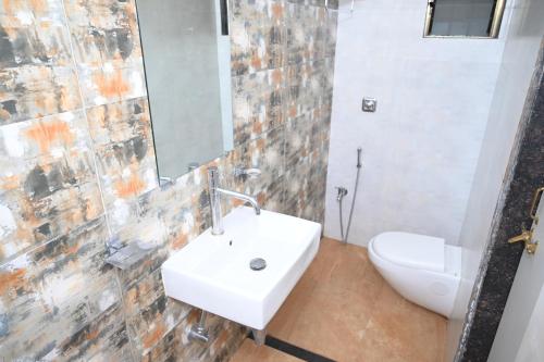 W łazience znajduje się umywalka, toaleta i lustro. w obiekcie Bagicha villa and cottage w mieście Mahabaleshwar