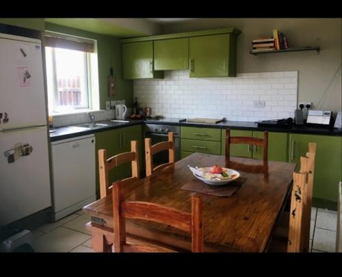 卡洛的住宿－Holiday house in quiet housing estate near Kilkenny，厨房配有木桌,上面放着一碗水果