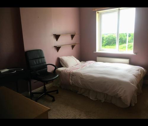 ein Schlafzimmer mit einem Bett, einem Stuhl und einem Fenster in der Unterkunft Holiday house in quiet housing estate near Kilkenny in Carlow