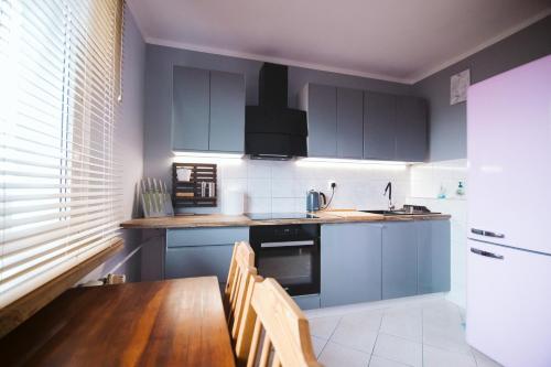 a kitchen with blue cabinets and a wooden table at Dwupokojowy Apartament 700 m od Szpital Prokocim in Kraków