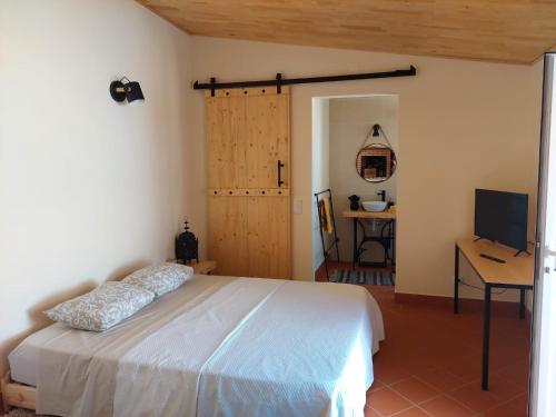 Dormitorio con cama, escritorio y TV en Casa Grés, en São Bartolomeu de Messines