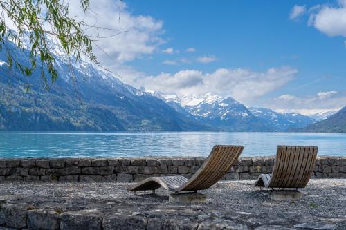 two chairs sitting next to a body of water at StayBrienz - Lake Brienz Family Holiday Apartment in Brienz