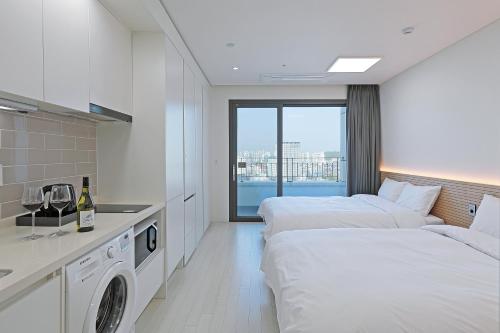 Habitación de hotel con 2 camas y lavadora en World Sky Residence Hotel en Sokcho