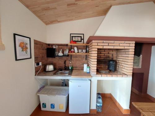 una pequeña cocina con fregadero y chimenea de ladrillo en Casa Grés, en São Bartolomeu de Messines