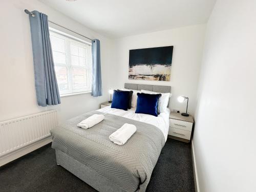 a bedroom with a large bed with blue pillows at Aristotle House by Blue Skies Stays in Stockton-on-Tees
