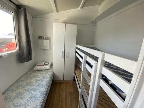 1 Schlafzimmer mit 2 Etagenbetten und einem Fenster in der Unterkunft Chalet situé dans un camping 4 étoiles - 4 à 6 personnes - KIRIO in Guidel