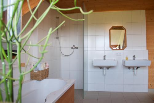 La salle de bains est pourvue de 2 lavabos, d'une baignoire et d'un miroir. dans l'établissement Stadt Land Freunde, à Wangen im Allgäu