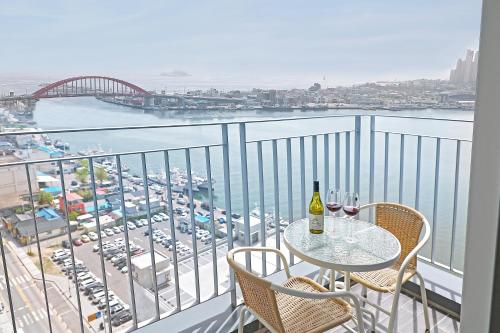 uma varanda com uma mesa e cadeiras e vista para um porto em World Sky Residence Hotel em Sokcho