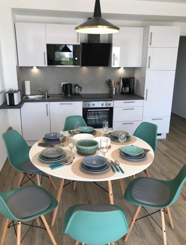 a kitchen with a table and chairs with plates and glasses at The Fehmarn Lodges - OASIS - in Fehmarn