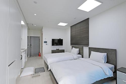 a bedroom with two beds and a tv in it at World Sky Residence Hotel in Sokcho