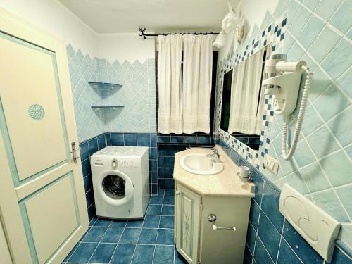 y baño de azulejos azules con lavabo y lavadora. en Sea View Homes CB, en Baja Sardinia