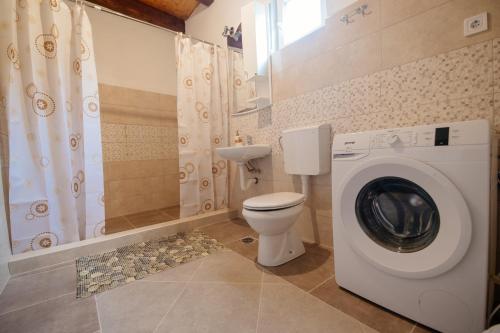 a bathroom with a washing machine and a toilet at Omni S Apartments in Bar