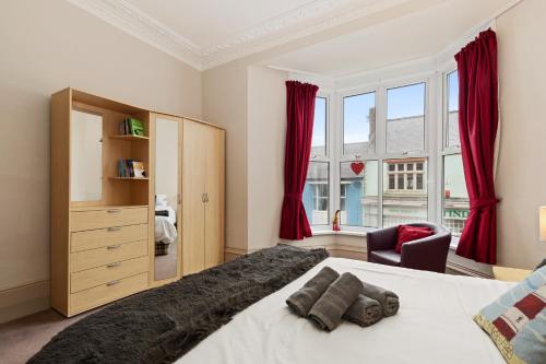um quarto com uma cama grande e cortinas vermelhas em Connaught House - Central Location Near the Beach em Tenby