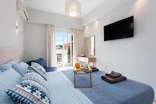 a bedroom with a blue bed and a television at Marietta's Resort by Konnect, Gouvia Corfu in Gouvia