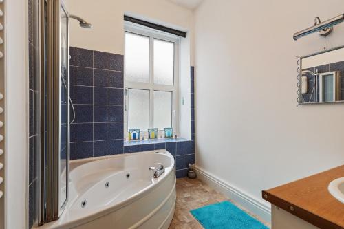 uma casa de banho com uma banheira, um lavatório e uma janela em Connaught House - Central Location Near the Beach em Tenby