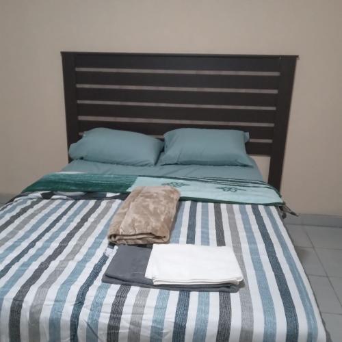 - un lit avec des draps et des oreillers à rayures bleus et blancs dans l'établissement Sandton guesthouse, 