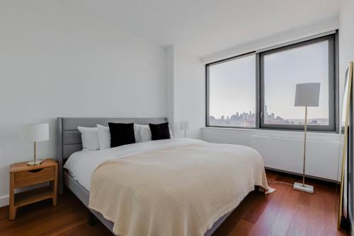 1 dormitorio blanco con 1 cama grande y 2 ventanas en Blueground Hudson Yards gym wd sports NYC-1483, en Nueva York